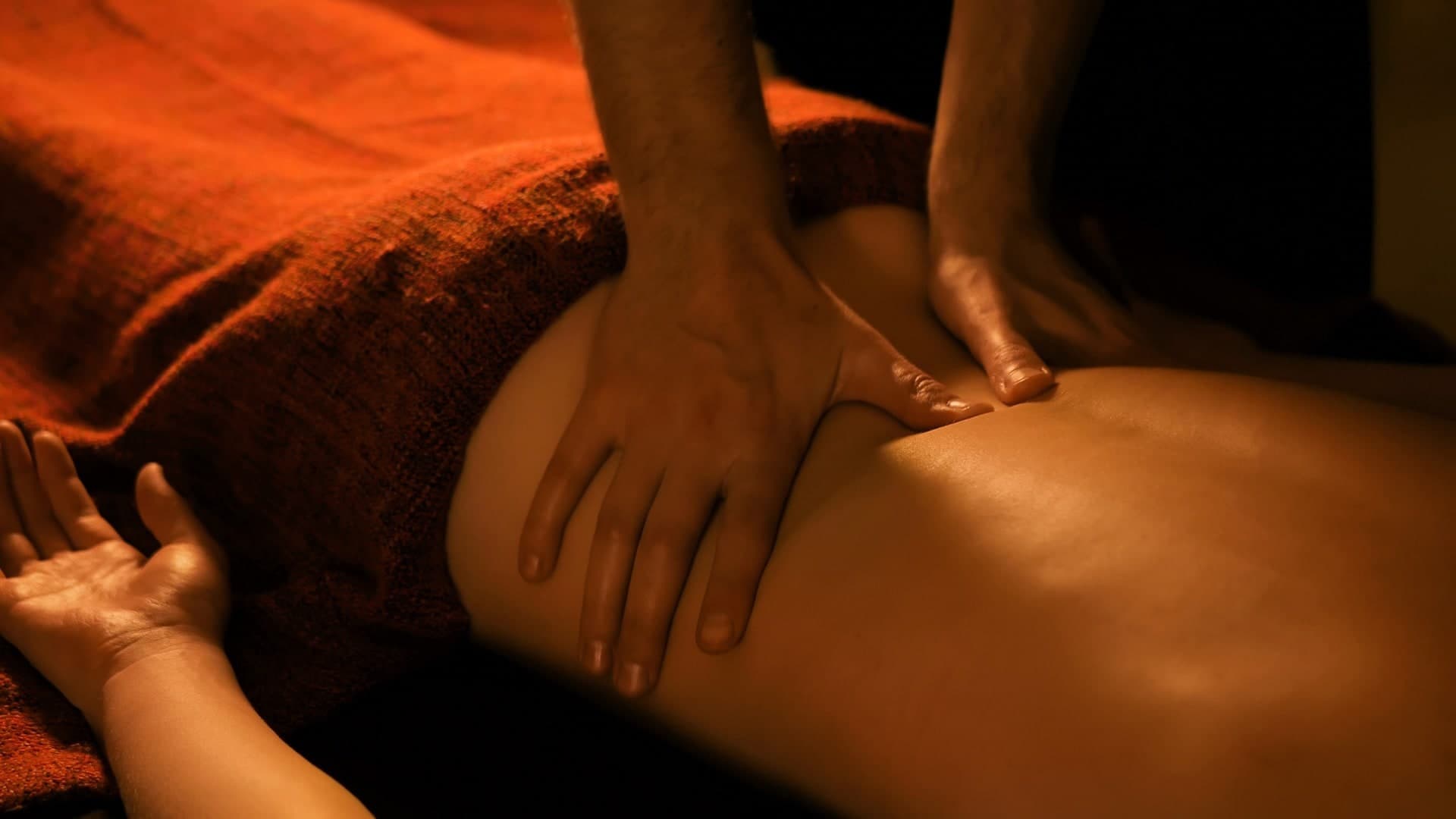 Registered massage therapist performing deep tissue massage on a client's back, warm ambient lighting
